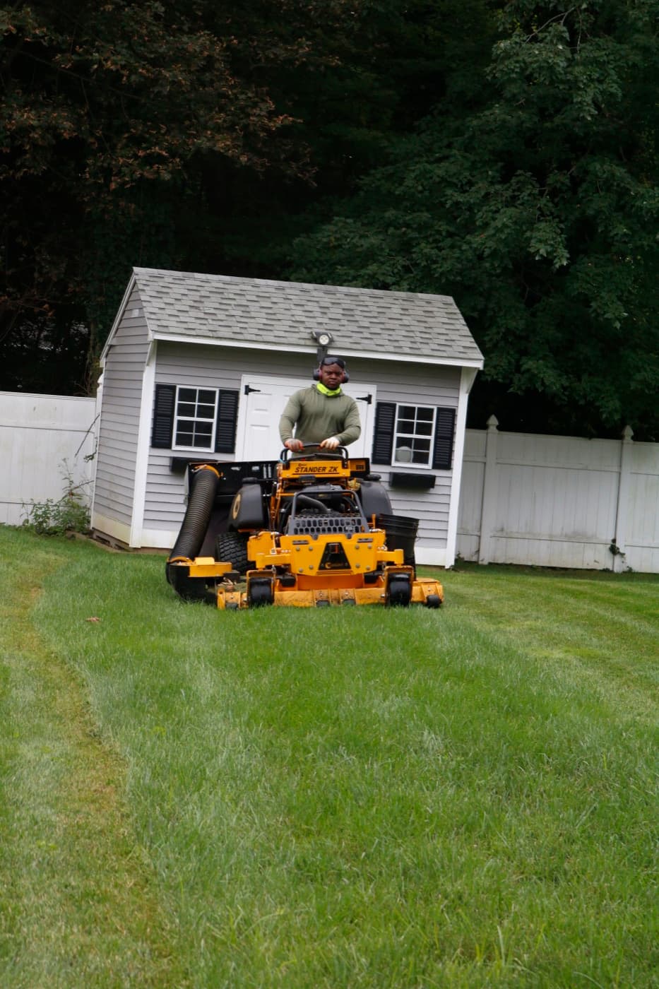 Mowing a backyard beside a storage shed